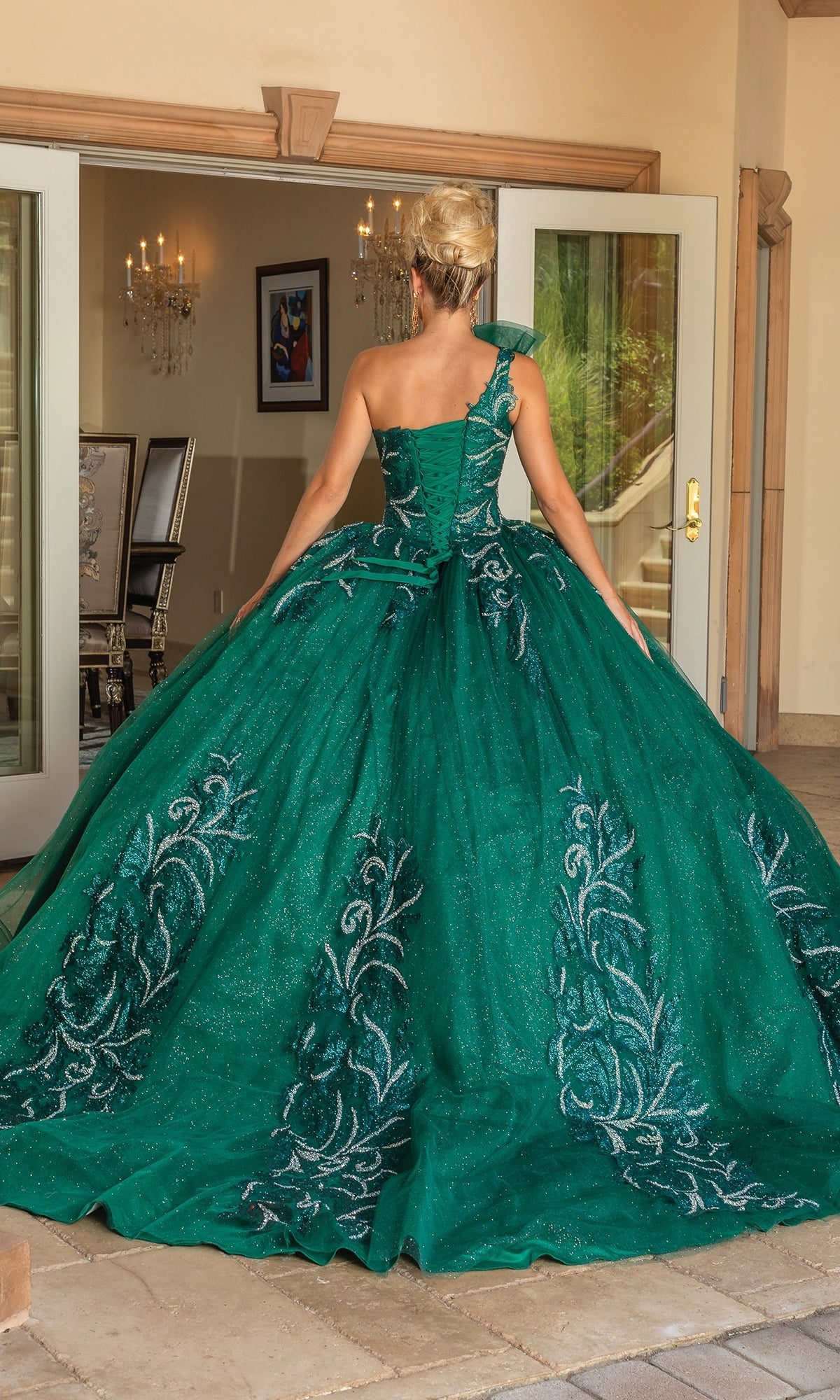 A woman wearing the Dancing Queen 1733 One-Shoulder Long Quince Dress stands with her back to the camera just outside double doors, about to enter an elegant room.